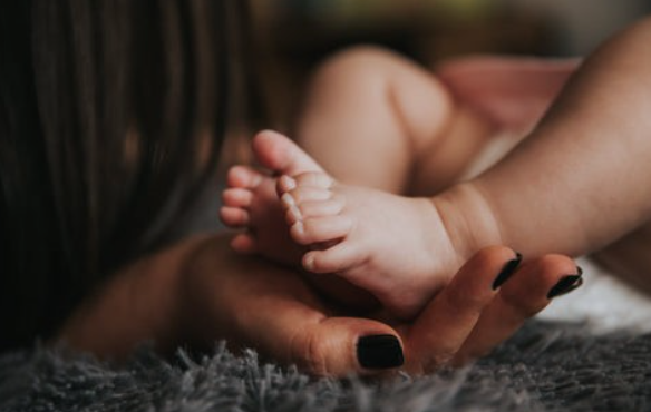 A parent holds a baby's feet. The baby has mild Eczema.