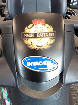A close up of Sir Robert's Invacare scooter's insignia.  The insignia reads 'NZ 26th Māori Battalion."