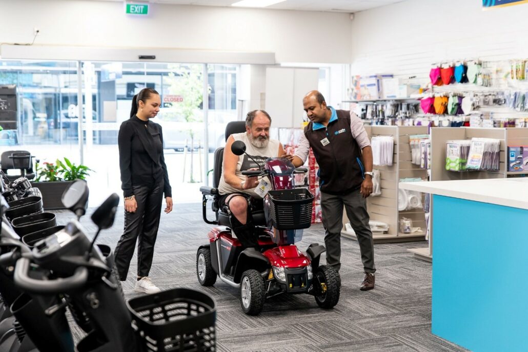 A man choosing a Mobility Scooter, receiving tips from Mobility Centre staff.