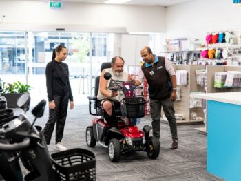 A man choosing a Mobility Scooter, receiving tips from Mobility Centre staff.