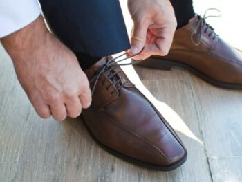 A man putting on a pair of specialist shoes.