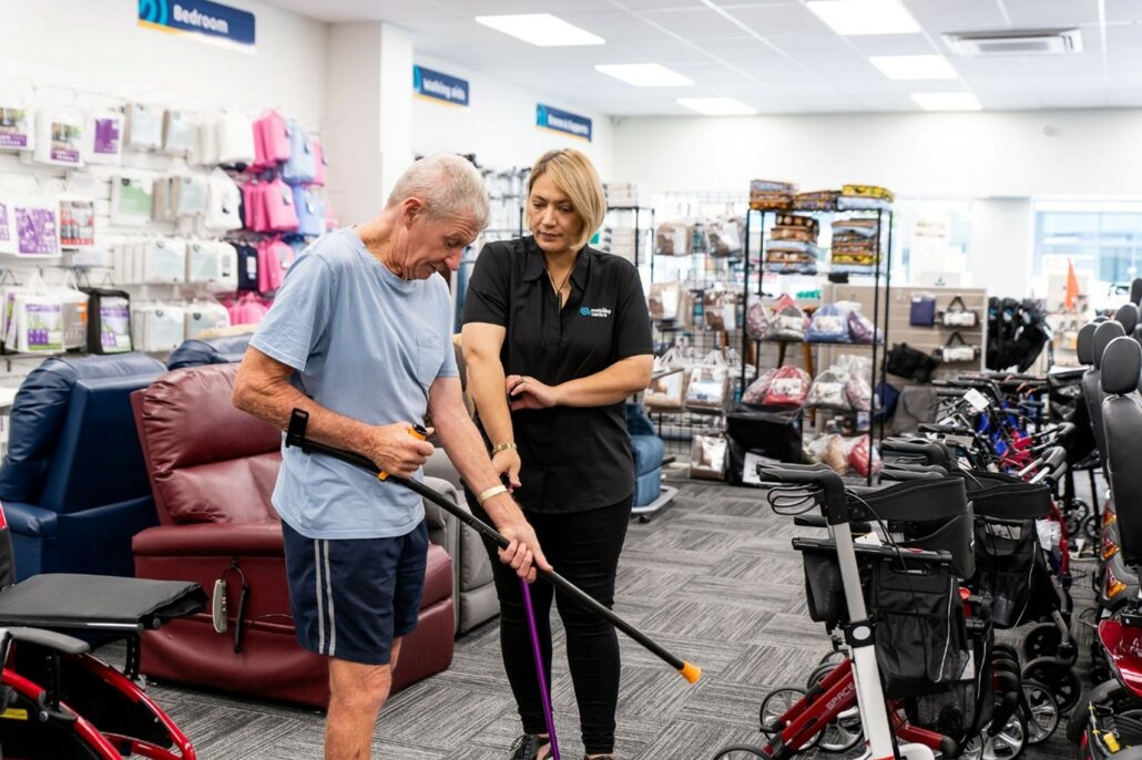 A man receiving advice from a Mobility Centre worker about choosing a walking stick.
