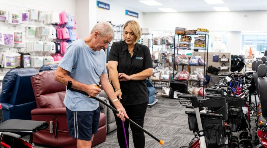 A man receiving advice from a Mobility Centre worker about choosing a walking stick.