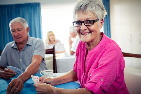 A man and a woman living with dementia are enjoying playing cards.