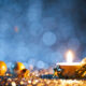 Lighted tea light and christmas ornaments on defocused blue and gold background.